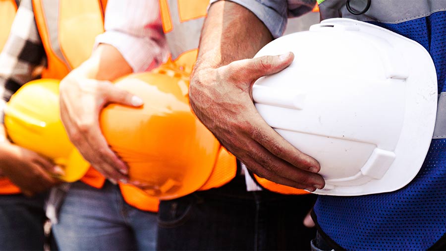 A line of workers holding hard hats in different colors