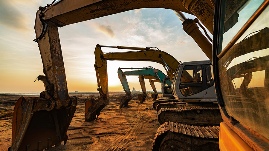 A row of excavators lined up at dusk