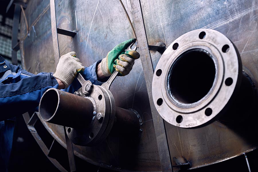 A worker tighting bolt on a large pipe flange