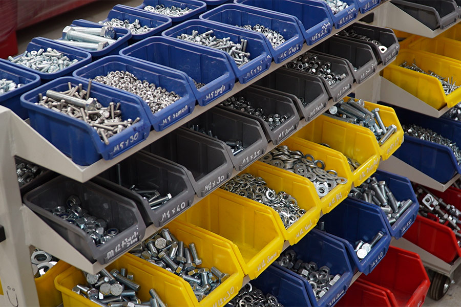 Nuts, bolts, and washers arrainged in trays at a factory.